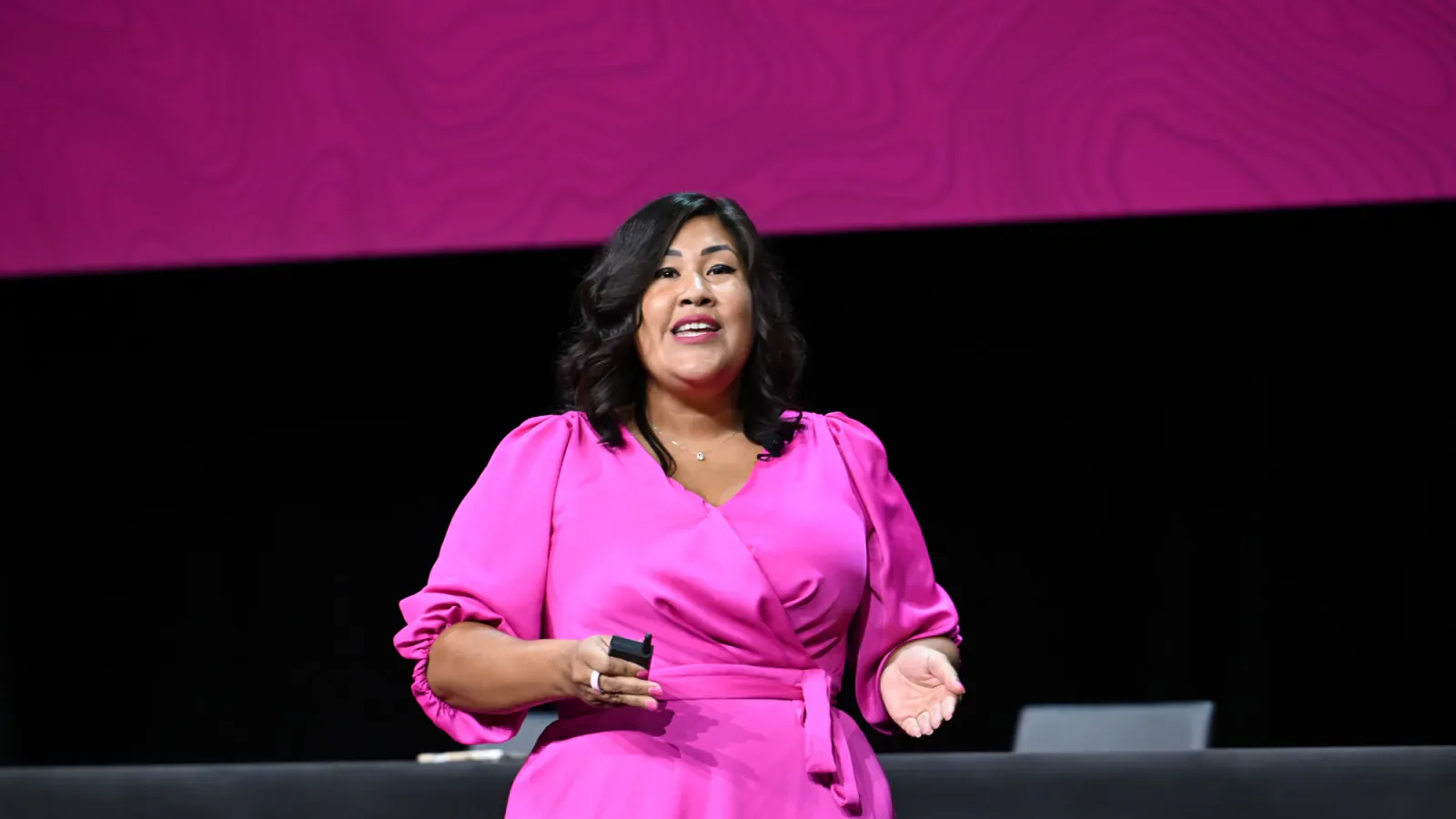 Flor De Maria McNally speaking on stage in a pink dress